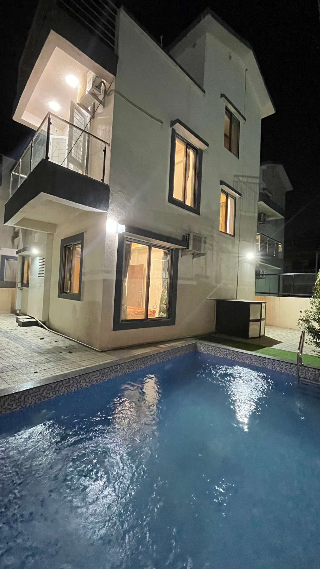 Saanjh villa private pool illuminated at night